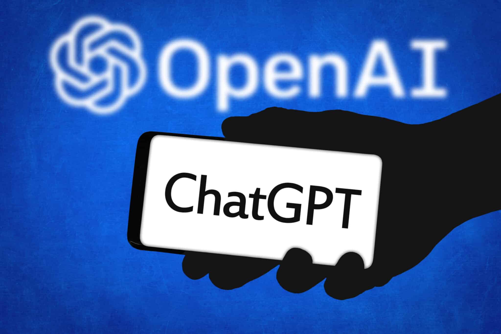 A picture of a silhouette hand holding a phone with ChatGPT written on it, with a blue background carrying OpenAI's logo and name